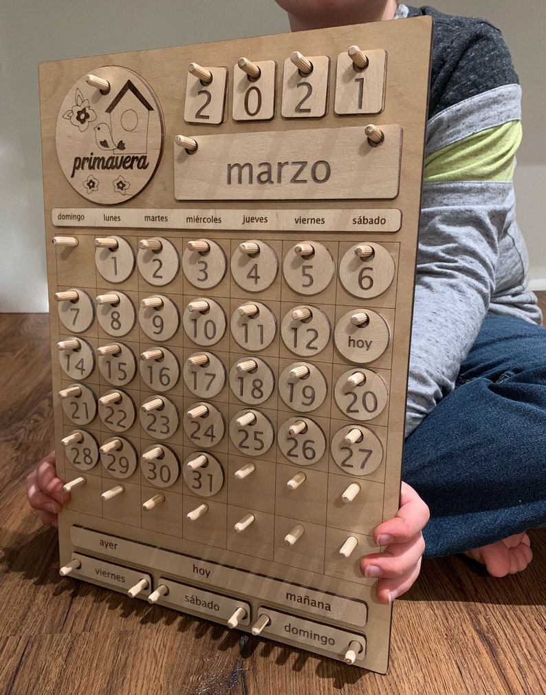 May include: Wooden calendar with a spring theme. The calendar features a birdhouse with a bird and the word "primavera" which means spring in Spanish. The calendar is for March 2021 and has days of the week and numbers 1 through 31.