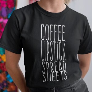 May include: Black t-shirt with white text that reads "COFFEE LIPSTICK SPREAD SHEETS"