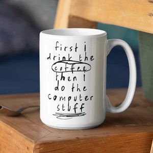 May include: White ceramic mug with black text that reads "first i drink the coffee then i do the computer stuff". The word "coffee" is circled.