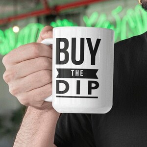 May include: White ceramic mug with black text that reads "BUY THE DIP".