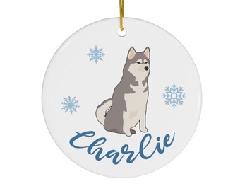 May include: A white ceramic Christmas ornament with a gray and white husky dog illustration, snowflakes, and the name "Charlie" in blue script.