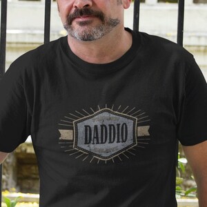 May include: A black t-shirt with a vintage-style graphic that says "World's Greatest Dad, Dad, Daddy, Old Man, Pops, Papa".
