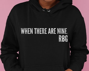 May include: Black hoodie with white text that reads "WHEN THERE ARE NINE. RBG".