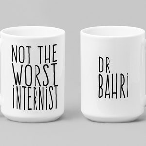 May include: Two white ceramic mugs with black text. One mug says "Not the worst internist" and the other mug says "Dr Bahri".