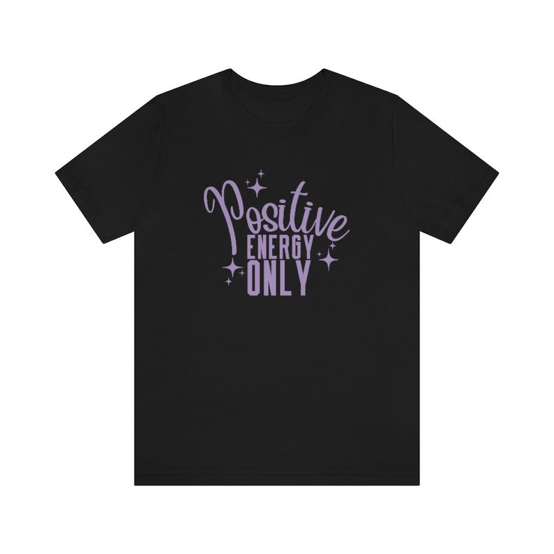 Op de afbeelding: Zwart T-shirt met een paars ontwerp met de tekst "Positive Energy Only" met sterren rond de tekst.