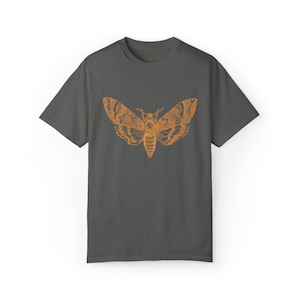 May include: A dark gray t-shirt with an orange silhouette of a moth printed on the front.