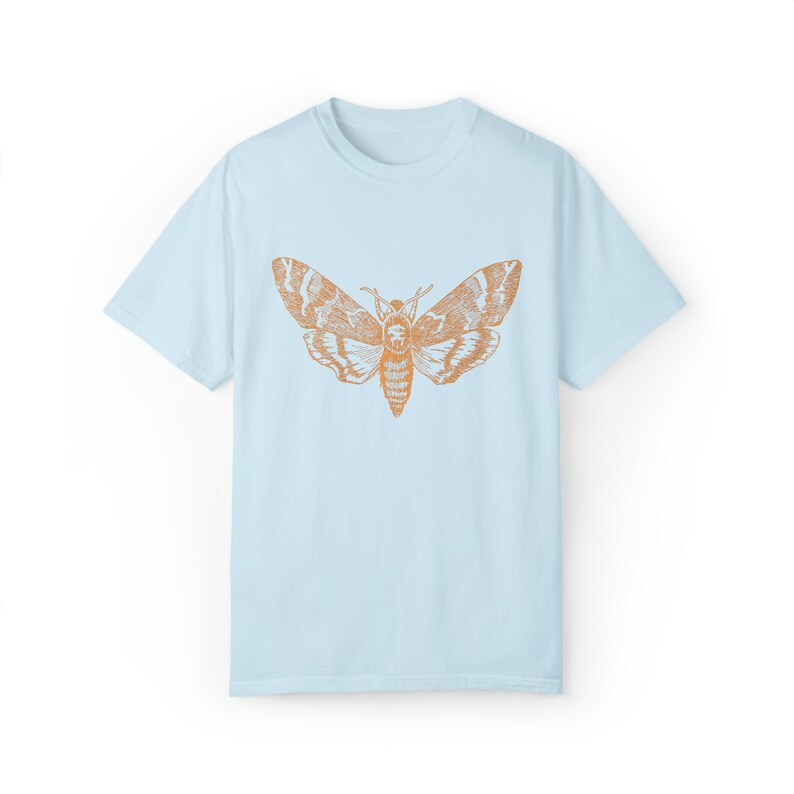 May include: A light blue t-shirt with an orange moth graphic printed on the front.