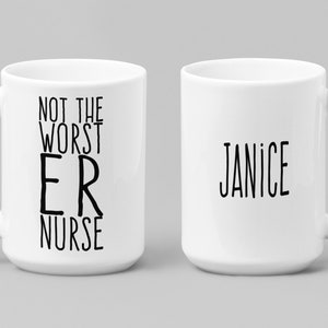 May include: White ceramic coffee mug with a black handle. The mug has the text "Not the worst ER nurse" on one side and the name "Janice" on the other side.