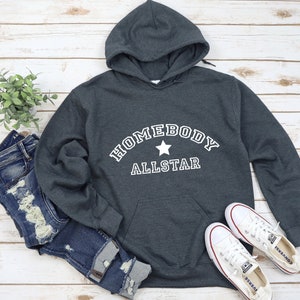 May include: A dark gray hooded sweatshirt with the text "Homebody Allstar" in white with a white star in between the words.