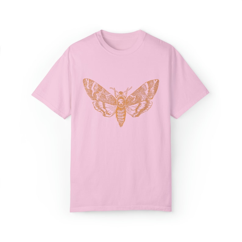 May include: A pink t-shirt with a vintage illustration of a moth in orange on the front.