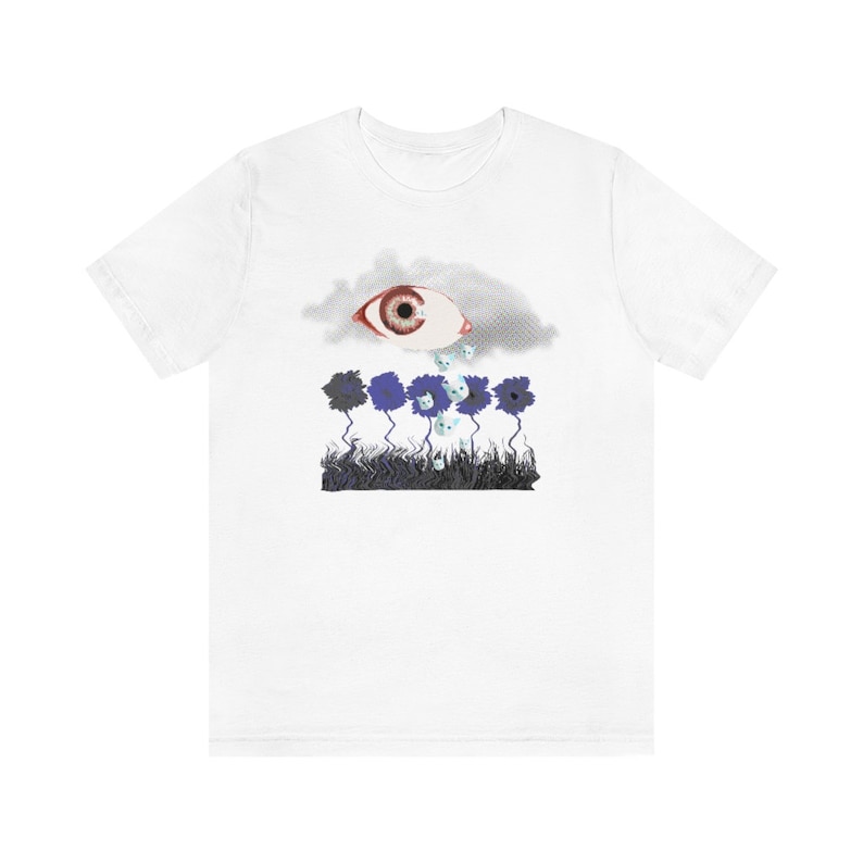 May include: White t-shirt with a graphic of a large eye inside a cloud crying blue teardrops onto a field of blue flowers.