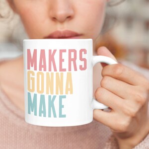 May include: White ceramic mug with the text "MAKERS GONNA MAKE" in a rainbow color scheme. The text is in a bold, sans-serif font.