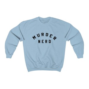 May include: A light blue sweatshirt with the text "MURDER NERD" printed in black.