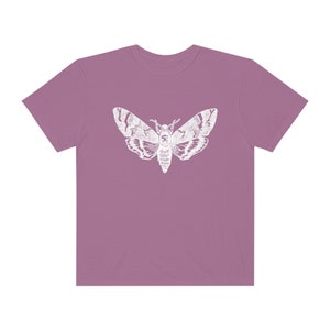 May include: A mauve t-shirt with a white silhouette of a moth printed on the front.