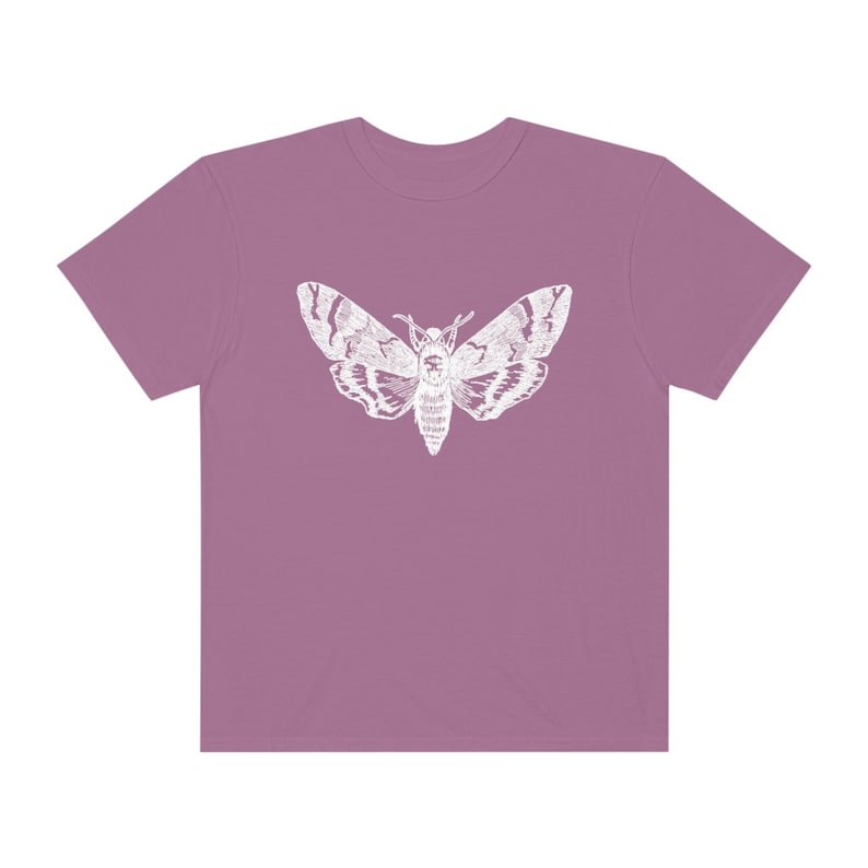 May include: A mauve t-shirt with a white silhouette of a moth printed on the front.