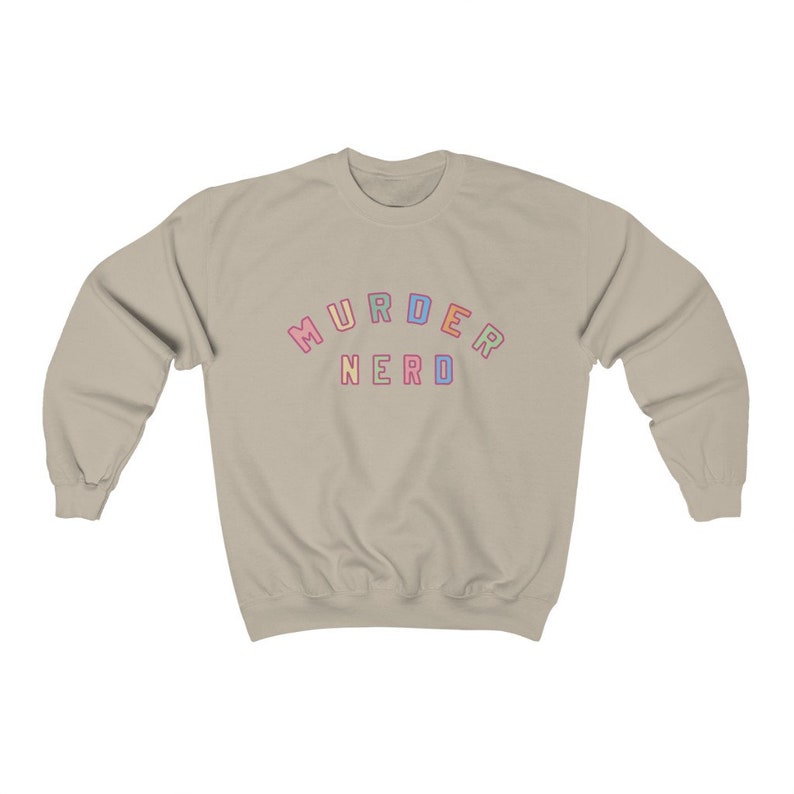 May include: A light beige sweatshirt with the text "MURDER NERDO" in rainbow colors.