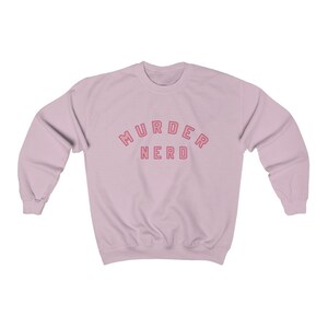 May include: A light pink sweatshirt with the text "MURDER NERD" in pink with a red outline.