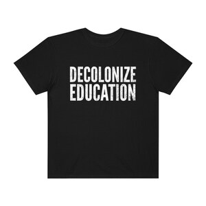 May include: Black t-shirt with the text "DECOLONIZE EDUCATION" in white, distressed lettering.