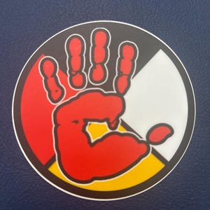 May include: A red handprint inside a circle with four colors: red, black, white, and yellow. The colors represent the four directions and the four races of humanity.