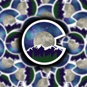 May include: A sticker featuring a stylized outline of the state of Colorado with a full moon, mountains, and a starry night sky.