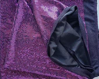 May include: Purple fabric with a sparkly, iridescent finish. The fabric is folded in half, revealing a black lining.