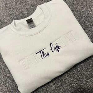 K&ouml;nnte beinhalten: Ein wei&szlig;es Sweatshirt mit dem gestickten Schriftzug "Take This life" in Marineblau und Wei&szlig;. Das Sweatshirt mit Rundhalsausschnitt ist aus weichem Material und f&uuml;r den l&auml;ssigen Gebrauch geeignet.