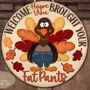 May include: Wooden round sign with a turkey wearing blue jeans and a red wattle. The sign reads "WELCOME, HOPE YOU BROUGHT YOUR FAT PANTS". Decorative fall leaves surround the turkey.