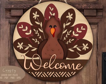 Puede incluir: Un letrero de bienvenida redondo de madera con un diseño de pavo. El pavo es marrón con una carúncula roja y un pico naranja, sobre un fondo marrón claro. La palabra "Welcome" está escrita en la parte inferior.