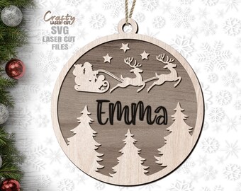 May include: A wooden Christmas ornament with a Santa Claus and reindeer design. The ornament is cut out and features the name "Emma".