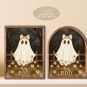 May include: Two framed Halloween ghost decorations. Each ghost wears a bow and has the text "hey BOO" below. The ghost is white with a lace-like design. One frame is rectangular, the other arched.