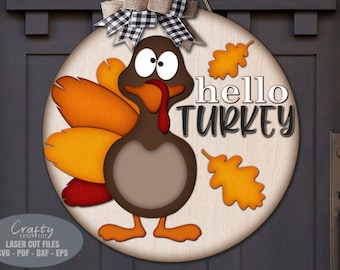 May include: A wooden round door hanger with a cartoon turkey with googly eyes and the text "hello turkey" in black lettering. The turkey has orange, red, and brown feathers and is surrounded by orange leaves.