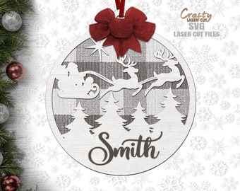 May include: A white wooden Christmas ornament with a black and white buffalo plaid design. The ornament features a silhouette of Santa Claus in a sleigh pulled by reindeer, with a star and pine trees. The word "Smith" is written in cursive at the bottom.