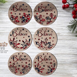 May include: Six wooden Christmas ornaments with the word "Believe" and snowflake designs. The ornaments are round with red, white, and blue accents. The ornaments are laser cut and have a rustic appearance.