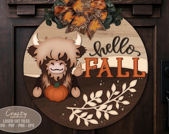 May include: A round wooden fall-themed door sign featuring a Highland cow holding a pumpkin. The sign says "hello FALL" in orange letters. A decorative bow with fall leaves sits at the top. The sign is laser cut.