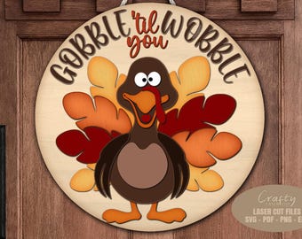 May include: A round wooden sign with a cartoon turkey design. The turkey has a brown body, orange feet, and a red wattle. The sign reads "GOBBLE 'til you WOBBLE" in a playful font, perfect for Thanksgiving decor.