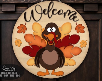 Puede incluir: Un letrero redondo de madera con un diseño de pavo para Acción de Gracias. El letrero presenta un pavo con cuerpo marrón, plumas naranjas y rojas, y la palabra "Bienvenido". Incluye hojas de otoño.
