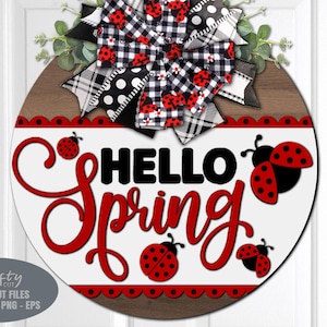 以下が含まれることがあります： 白い背景に赤い文字で「Hello Spring」と書かれた丸い木製の看板。看板は、白黒のチェック柄のリボン、赤と黒のテントウムシ、赤い波状の縁取りで飾られています。