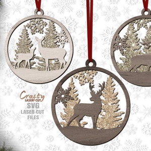 May include: Three wooden Christmas ornaments with a glitter finish. Each ornament features a silhouette of a deer in a forest setting with snowflakes.