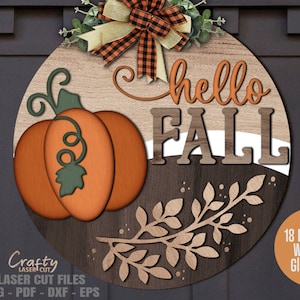 Könnte beinhalten: Ein rundes Holzschild mit dem Text "hello fall" in braunen und orangen Buchstaben. Auf der linken Seite des Schildes befindet sich ein Kürbis mit einem grünen Stiel. Das Schild ist mit einem braunen und weißen Blattwerk verziert.