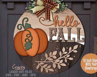 May include: A round wooden sign with the text "hello fall" in brown and orange lettering. A pumpkin with a green stem is on the left side of the sign. The sign is decorated with a brown and white leafy branch.
