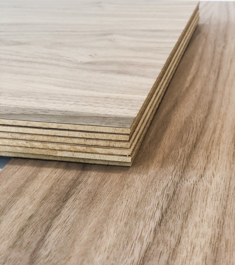 May include: A stack of wood veneer sheets, showing the layers of plywood. The top sheet has a light brown wood grain pattern.