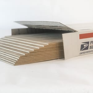May include: A stack of beige ceramic tiles in a cardboard box labeled "PRIORITY MAIL" from the United States Postal Service.