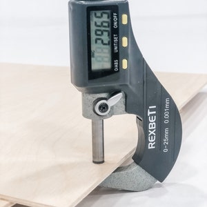 K&ouml;nnte beinhalten: Eine schwarze digitale Schieblehre misst ein St&uuml;ck Holz. Die Schieblehre zeigt 29,65 mm an. Die Schieblehre ist mit "REXBETI" und "0-25 mm 0,01 mm" beschriftet.