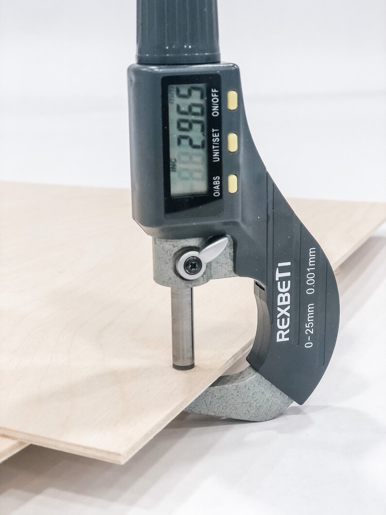 K&ouml;nnte beinhalten: Eine schwarze digitale Schieblehre misst ein St&uuml;ck Holz. Die Schieblehre zeigt 29,65 mm an. Die Schieblehre ist mit "REXBETI" und "0-25 mm 0,01 mm" beschriftet.