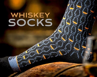 Puede incluir: Calcetines negros con un patrón de vasos de whisky naranja y azul. Los calcetines están sobre un barril de madera. El texto "WHISKEY SOCKS" está en el fondo.