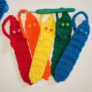 Puede incluir: Seis marcapáginas de ganchillo en un arcoíris de colores, rojo, naranja, amarillo, verde, azul y morado. Cada marcapáginas tiene ojos saltones y un lazo en la parte superior.
