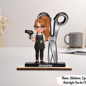 Puede incluir: Una figura de una peluquera sosteniendo un secador de pelo y de pie junto a unas tijeras plateadas grandes. La figura tiene una cola de caballo, gafas y un delantal. La base está grabada con el nombre "Jennifer". El texto en la parte inferior dice "Nombre, Tono de piel, Color de ojos, Peinado se puede cambiar".