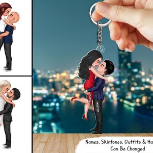 Puede incluir: Un llavero personalizado con una pareja en un abrazo romántico. La mujer lleva un vestido rojo y el hombre un traje azul. El llavero está hecho de acrílico y tiene un acabado brillante. Los nombres "Jessica" y "William" están impresos en el llavero.