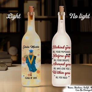 May include: A personalized graduation gift, a clear glass bottle with a cork top, decorated with a graduation cap and the text "Julia Martin, Class of 2025". The bottle is illuminated from within, creating a warm glow. The other side of the bottle features the text "Behind you all your memories, Before you all your dreams, Around you all who love you, Within you all you need."