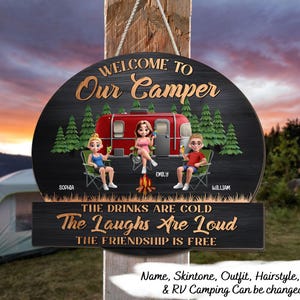 May include: A round, black wooden sign with the text "Welcome to Our Camper." It features a red camper, three cartoon figures, and the phrases "The Drinks Are Cold," "The Laughs Are Loud," and "The Friendship Is Free."
